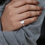 Hand wearing a diamond ring with a checkered fabric background

