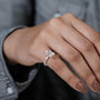 Close-up of a hand wearing a diamond ring with a blurred background

