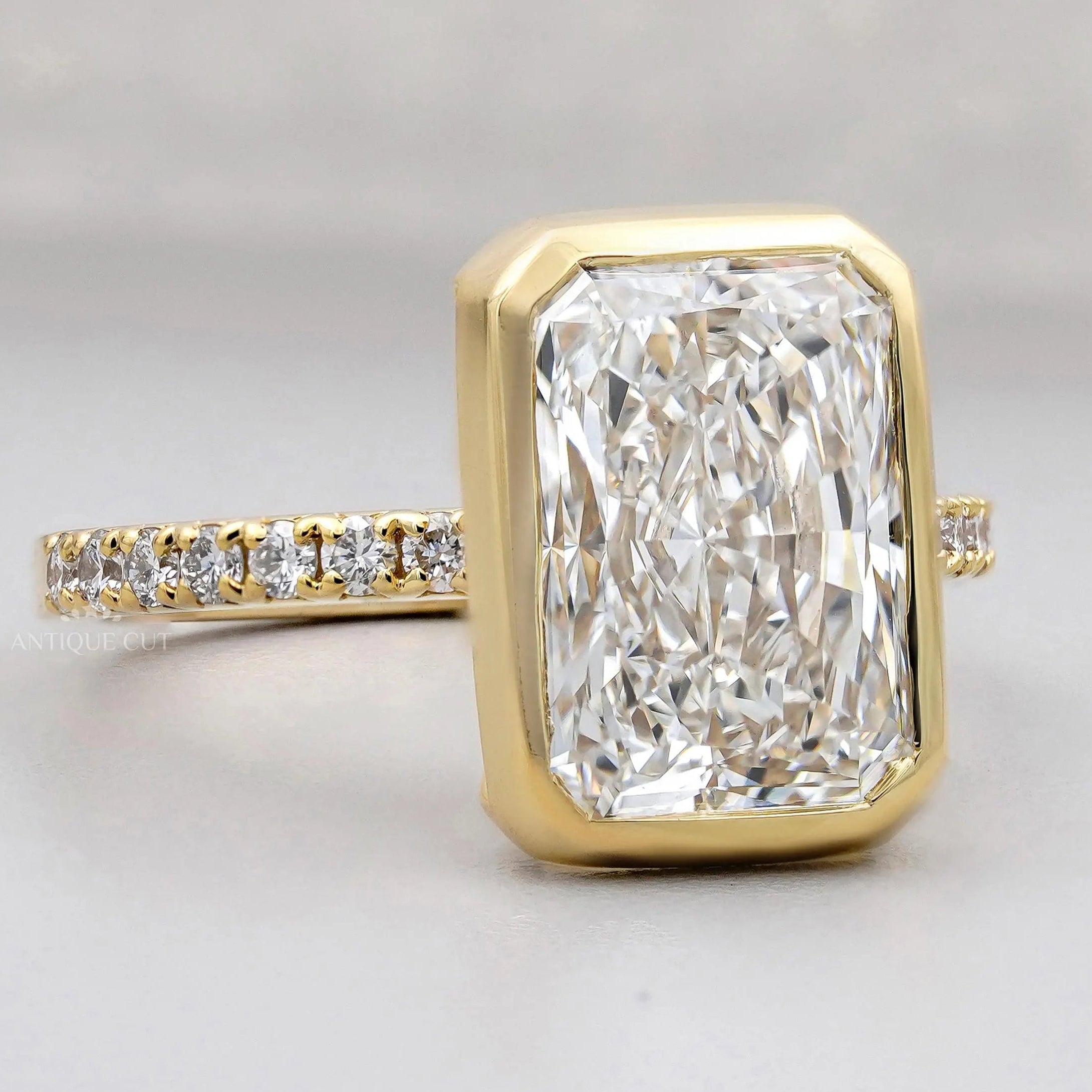 Gold ring with a large diamond and smaller diamonds on the band against a gray background