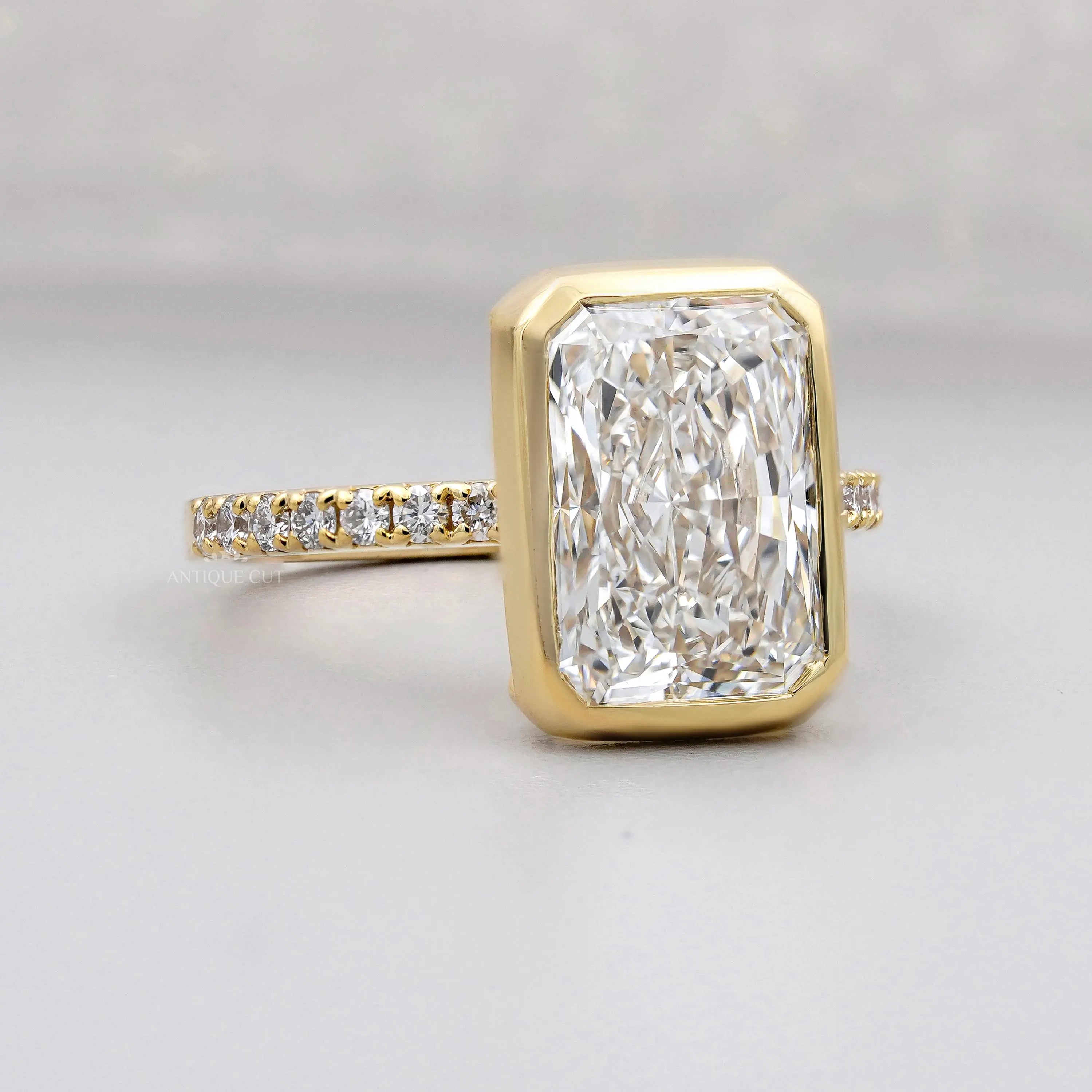 Gold ring with a large diamond and smaller diamonds on the band against a gray background