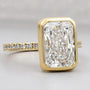 Gold ring with a large diamond and smaller diamonds on the band against a gray background
