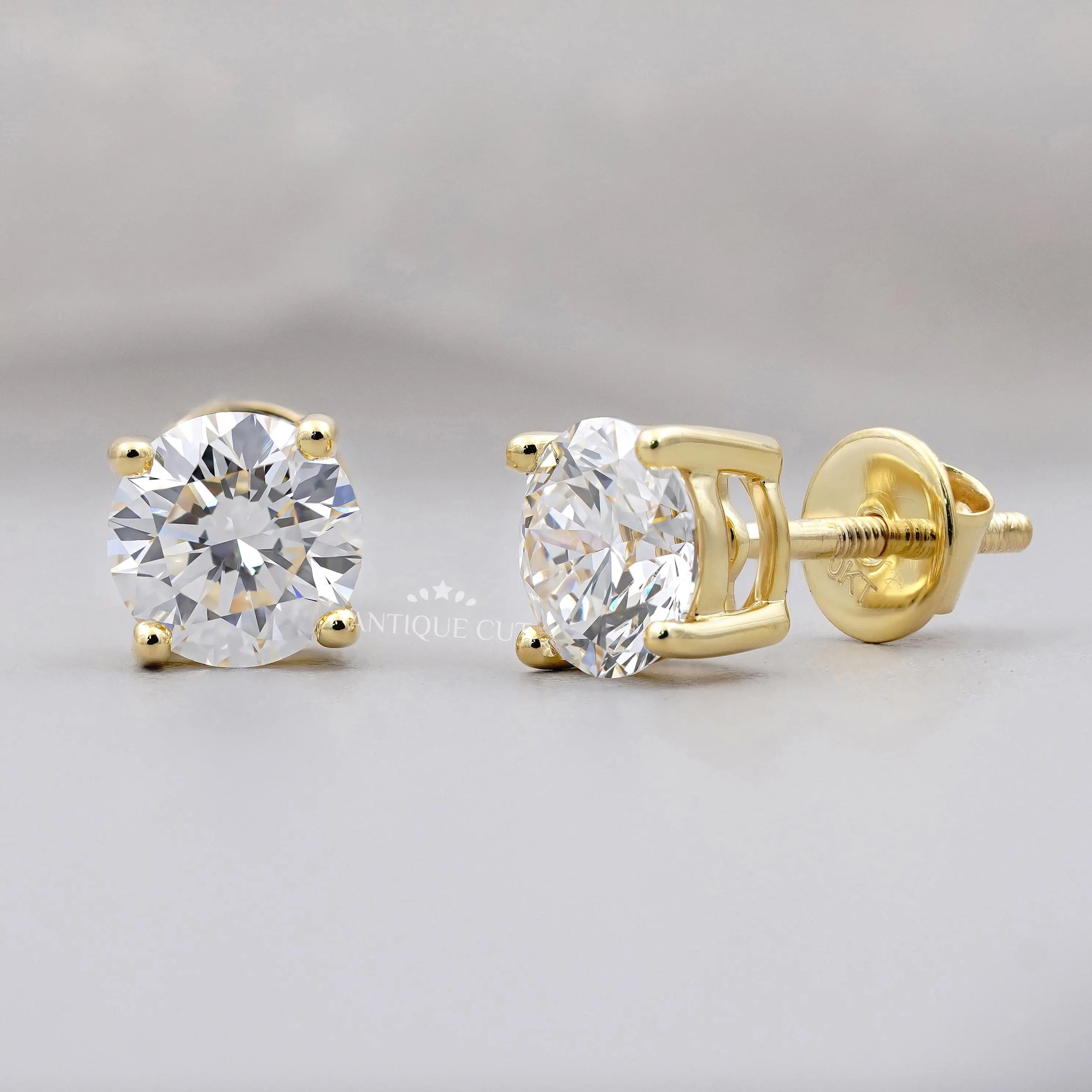Gold stud earrings with clear gemstones on a gray background
