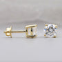 Gold stud earrings with clear gemstones on a light gray background