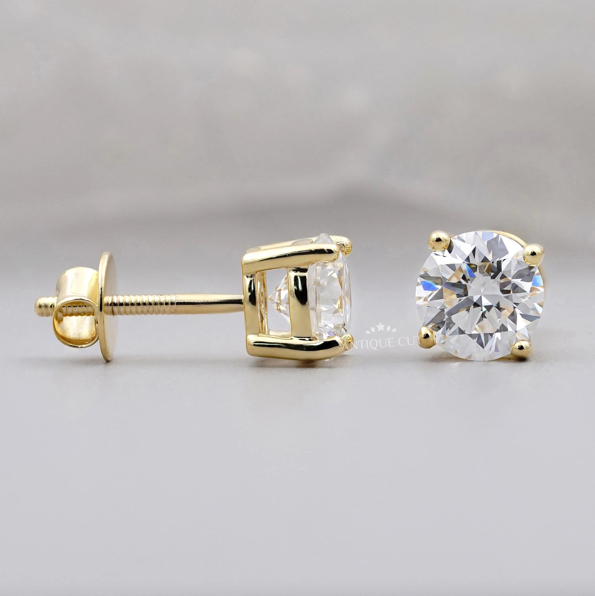 Gold stud earrings with clear gemstones on a light gray background