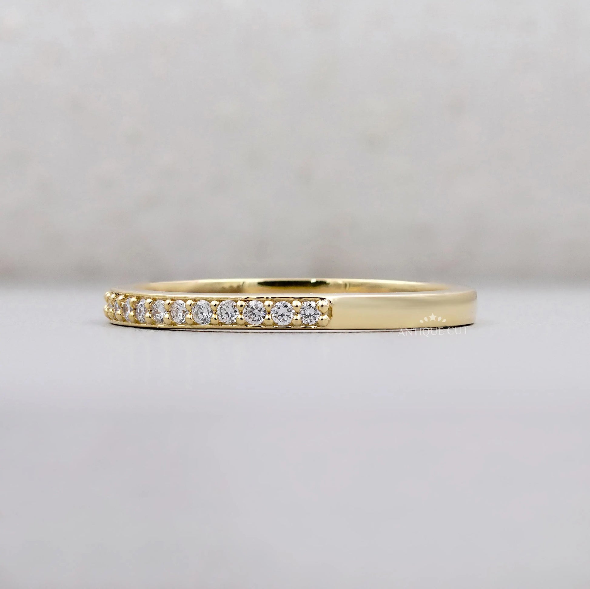 Gold ring with small diamonds on a light gray background
