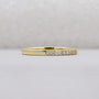 Gold ring with small diamonds on a light gray background
