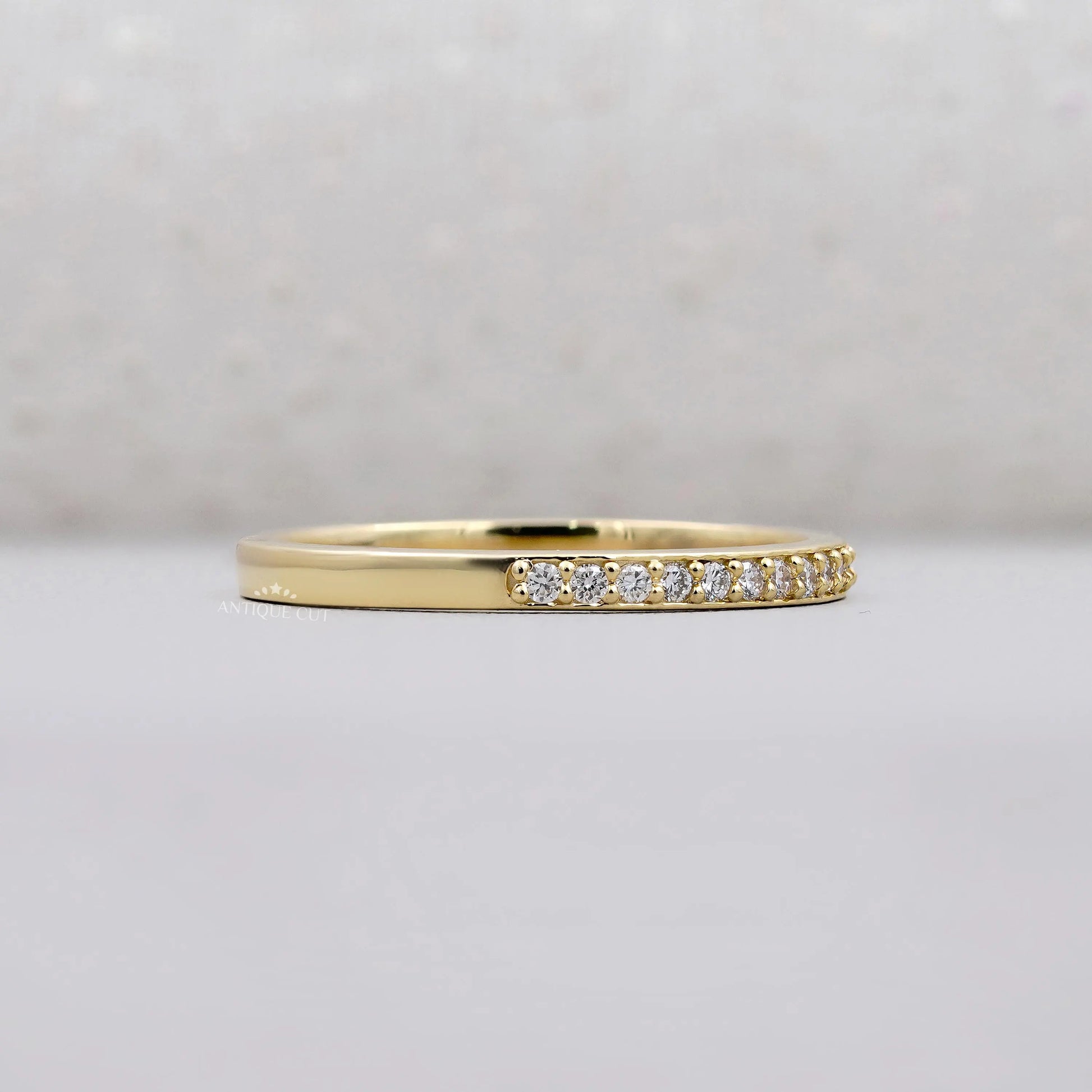 Gold ring with small diamonds on a light gray background