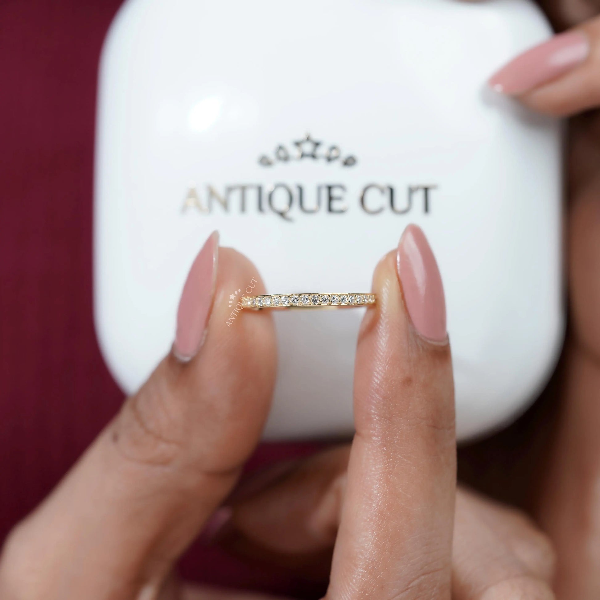 Gold ring being held by a hand against a white background with 'ANTIQUE CUT'