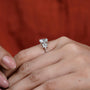 Diamond ring on a finger with a blurred red background

