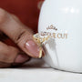 Gold ring with a diamond held against a white mug with 'Antique Cut' branding.

