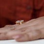 Gold ring with diamonds on a person's finger against a blurred red background

