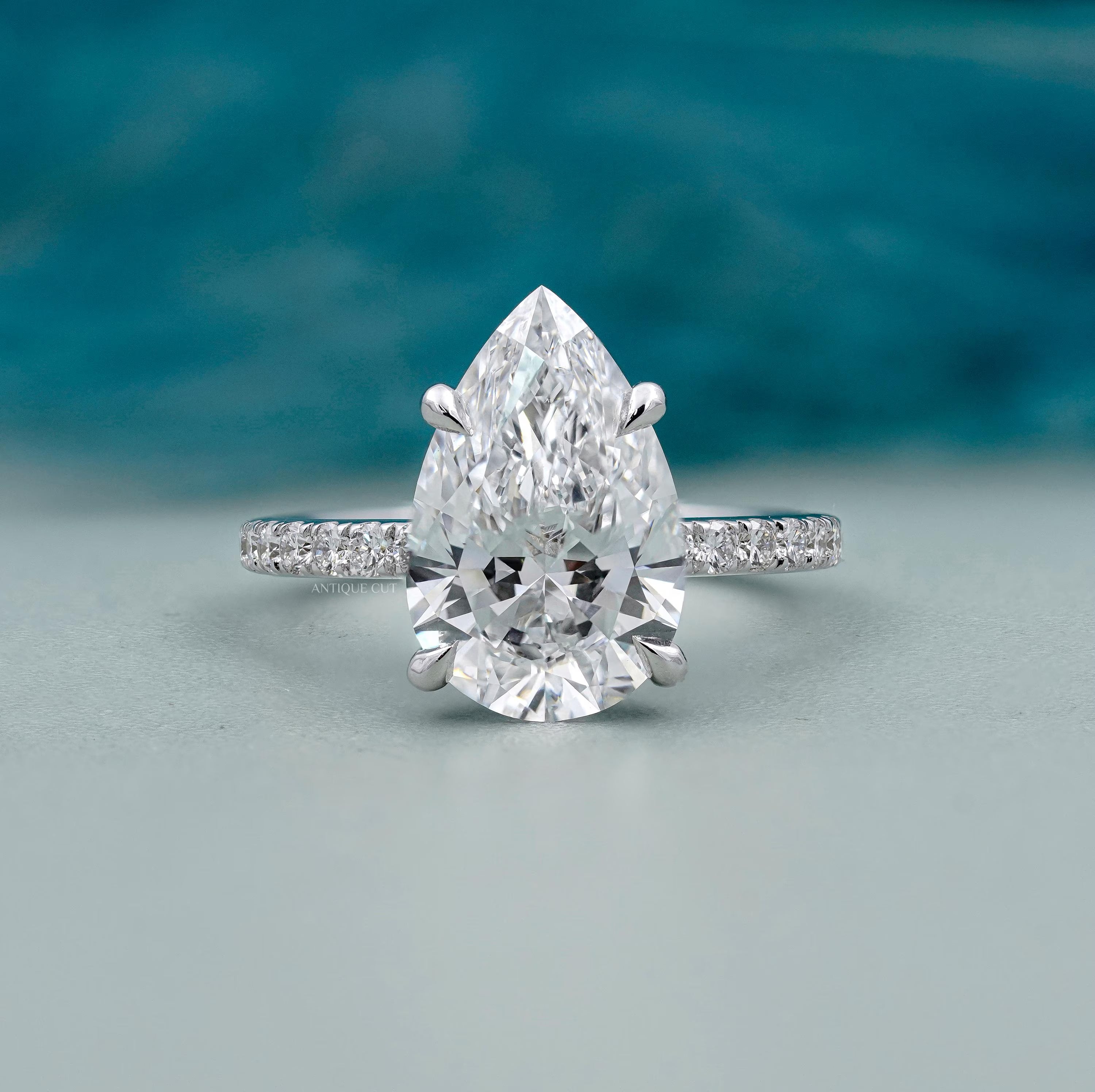 Pear shaped diamond ring with round side stones in white gold