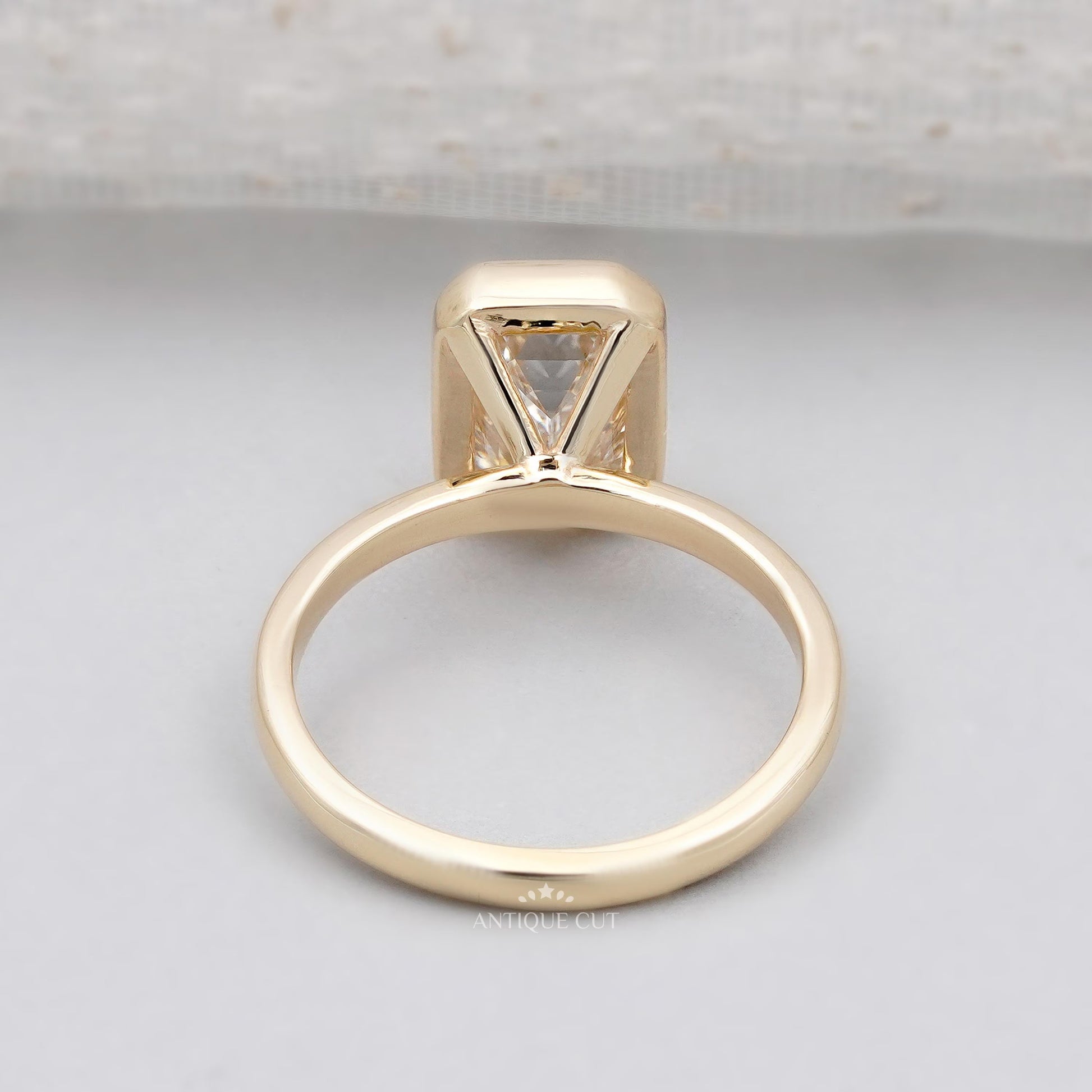 Emerald cut diamond ring with gold bezel setting close-up