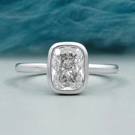 Cushion cut engagement ring with bezel set diamond
