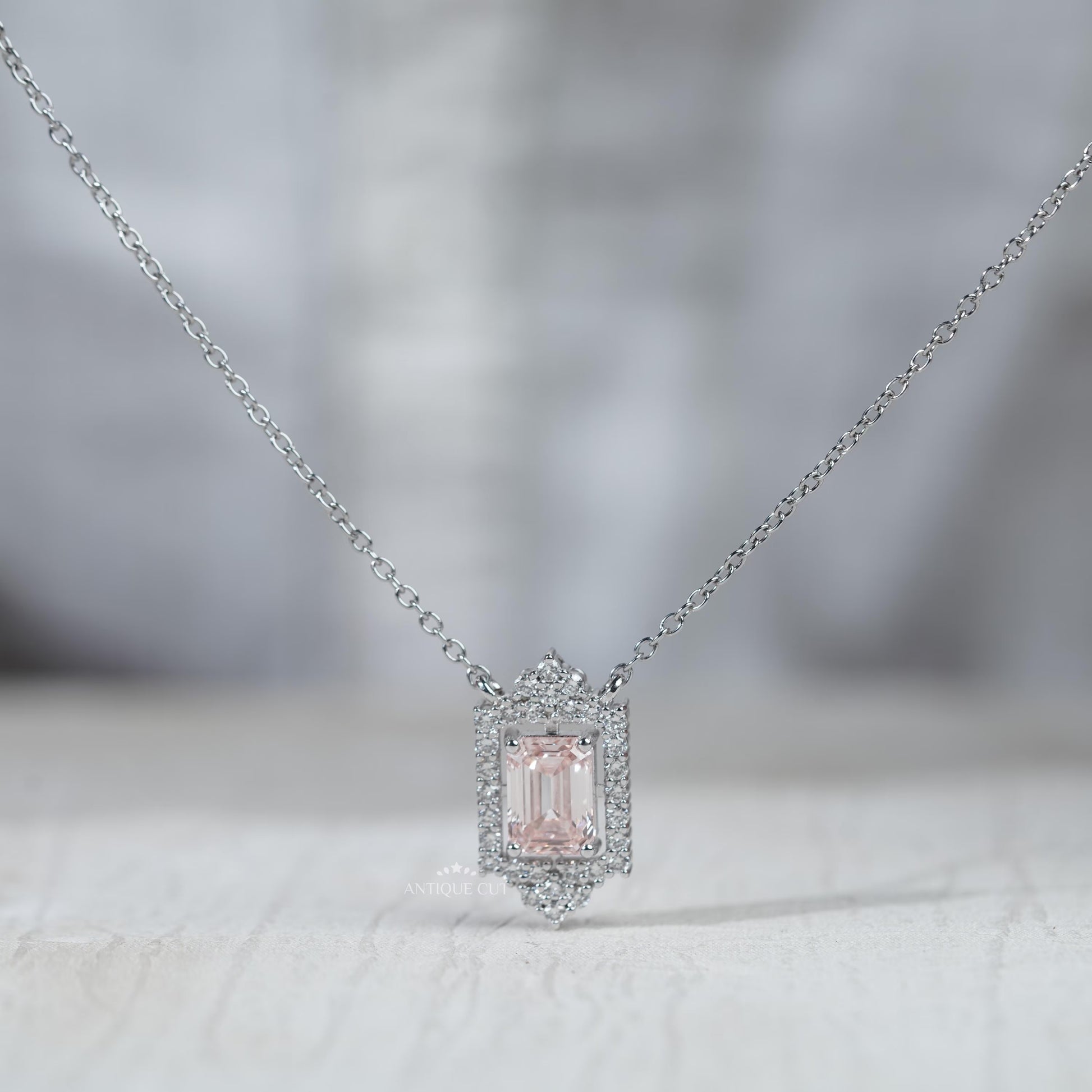 White gold emerald pendant with round diamond halo