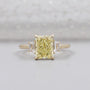 Radiant fancy yellow diamond ring in yellow gold with trapezoid side stones