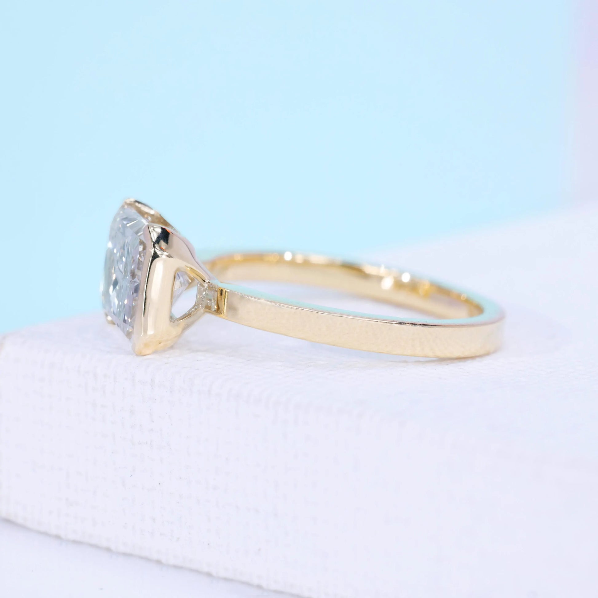 Half bezel engagement ring with radiant cut diamond and open gallery setting