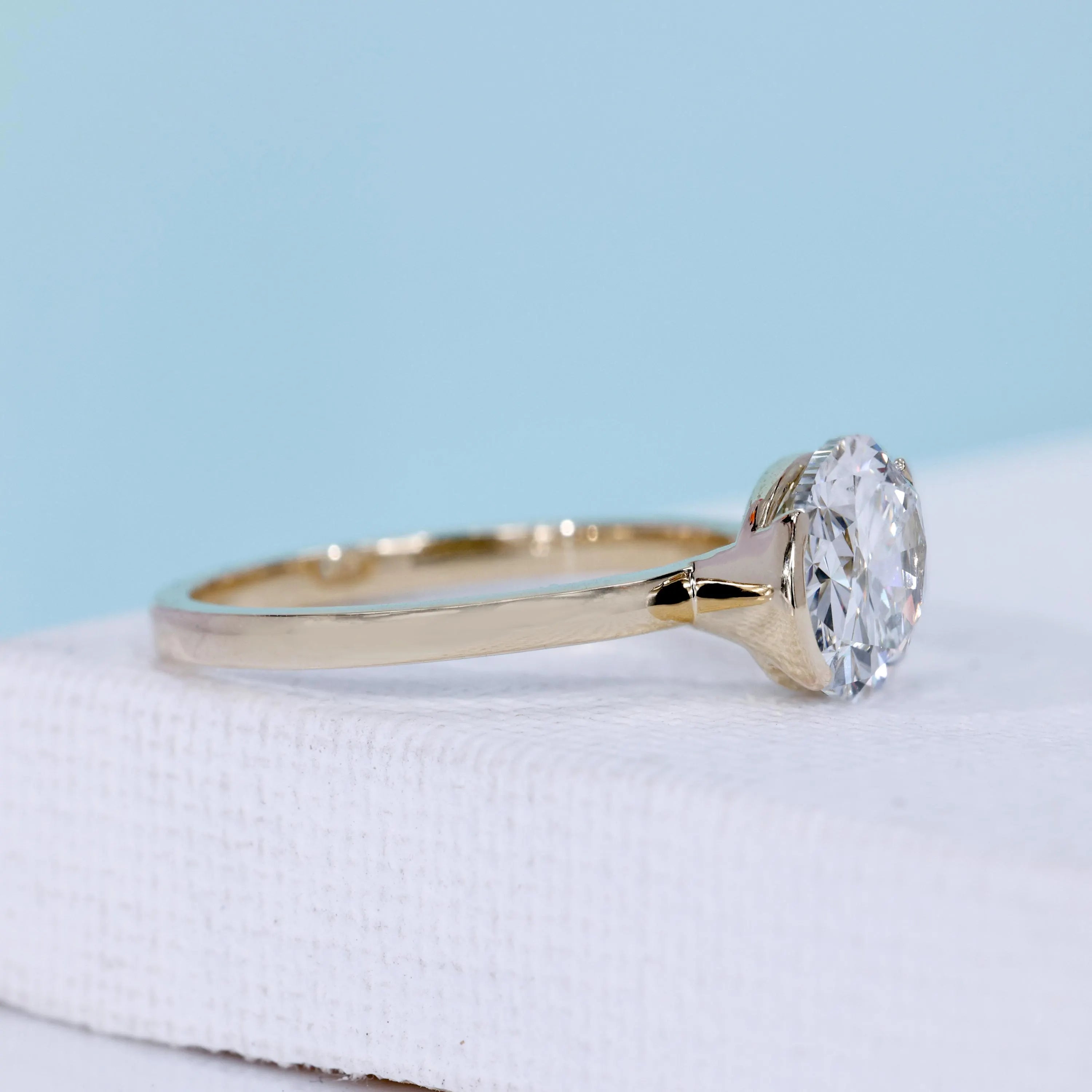 East west oval ring with half bezel setting and yellow gold design
