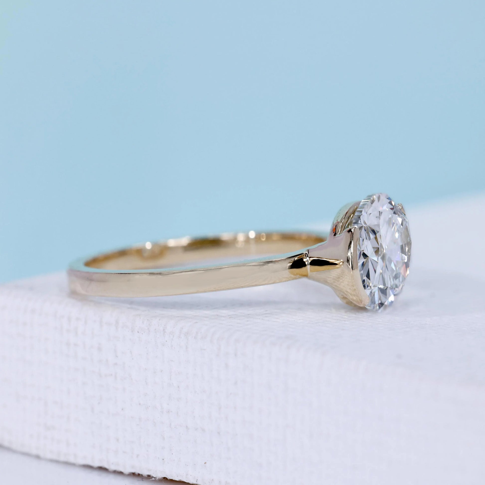 East west oval ring with half bezel setting and yellow gold design