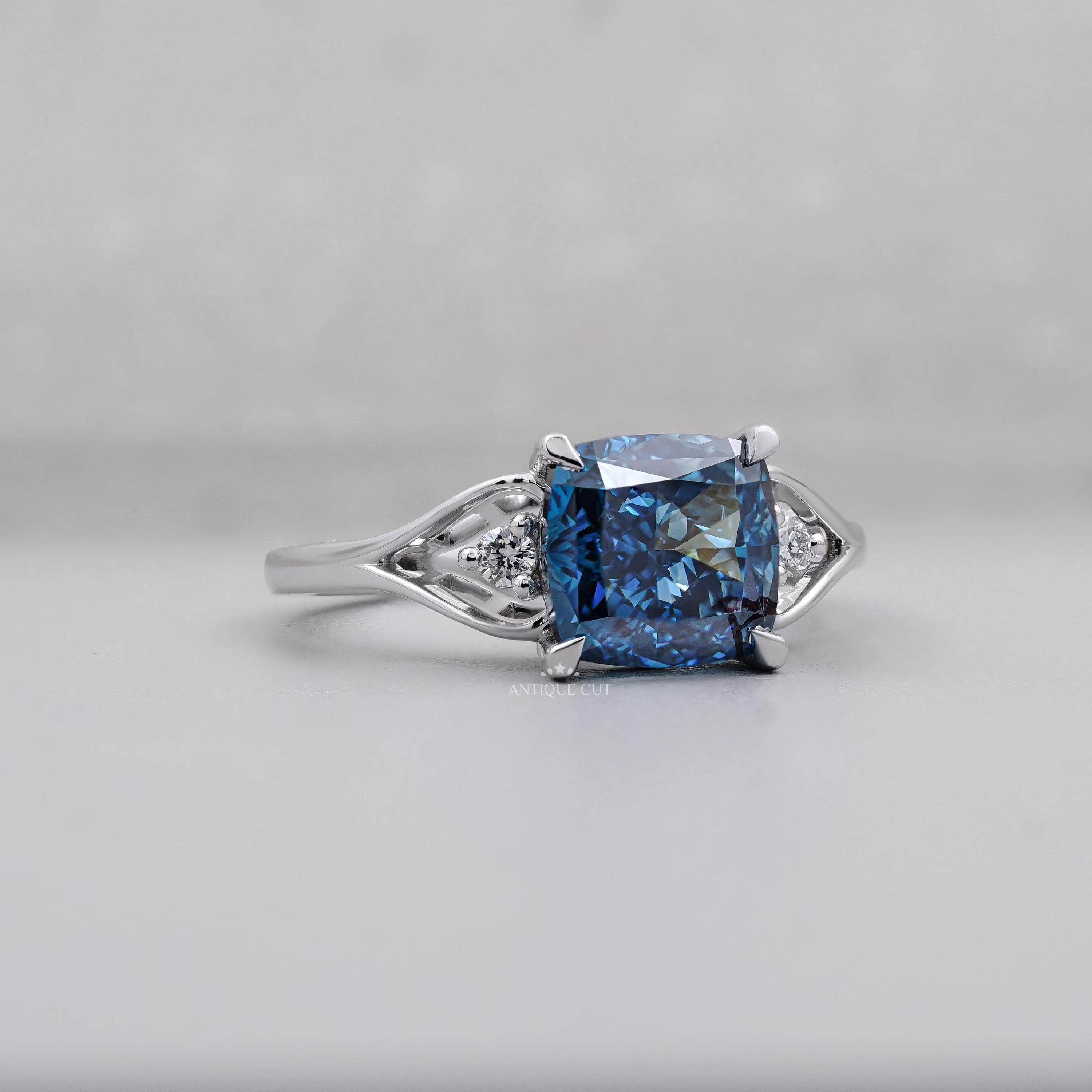 Fancy blue cushion cut diamond engagement ring with round side stones