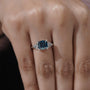 Round side stone engagement ring with cushion cut blue diamond