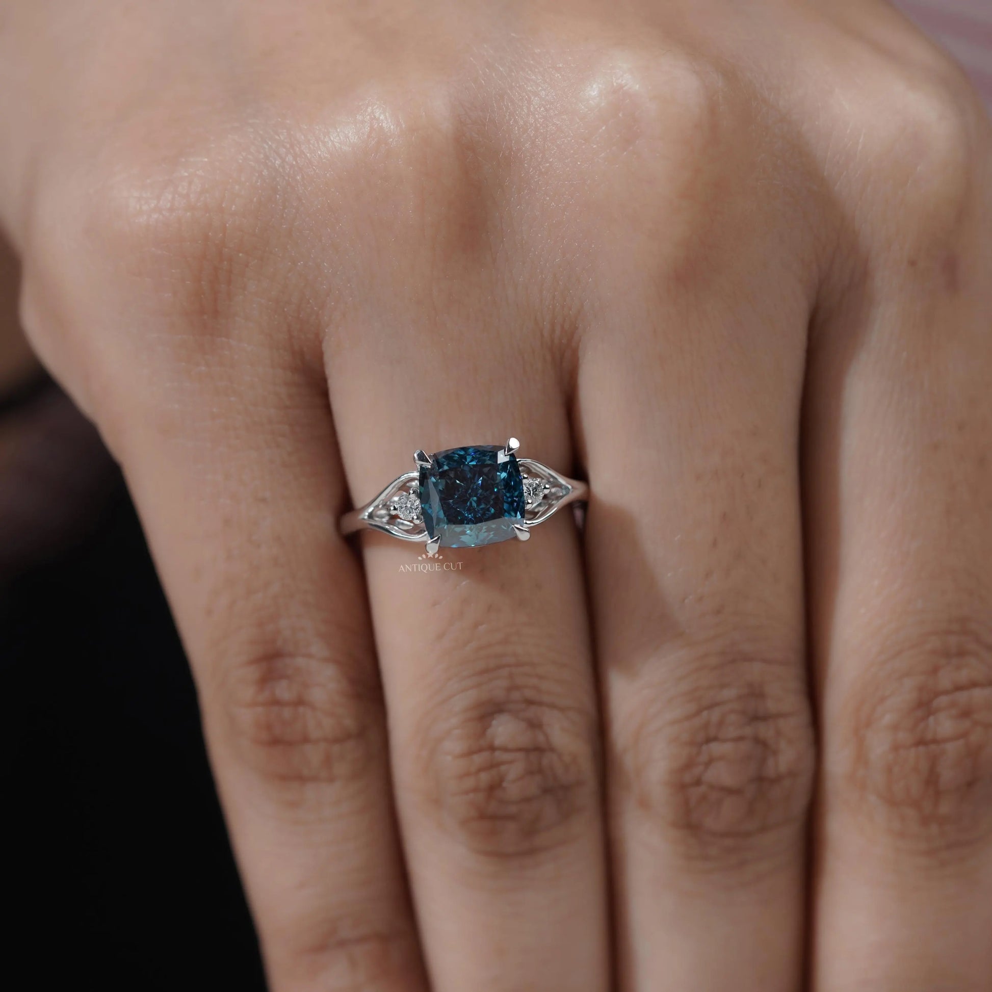 Round side stone engagement ring with cushion cut blue diamond