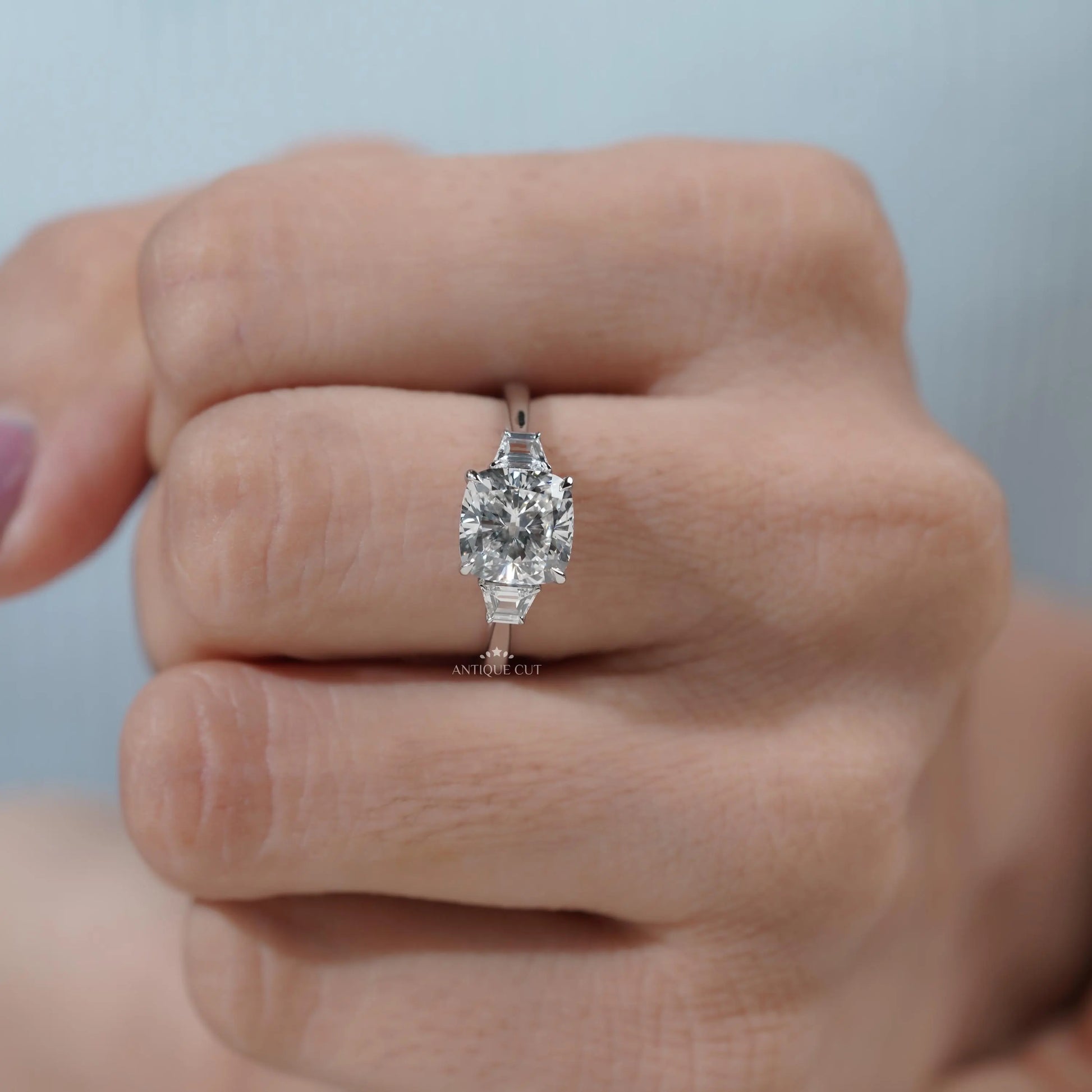 Minimalist engagement ring design with cushion cut diamond and baguette accents in white gold.