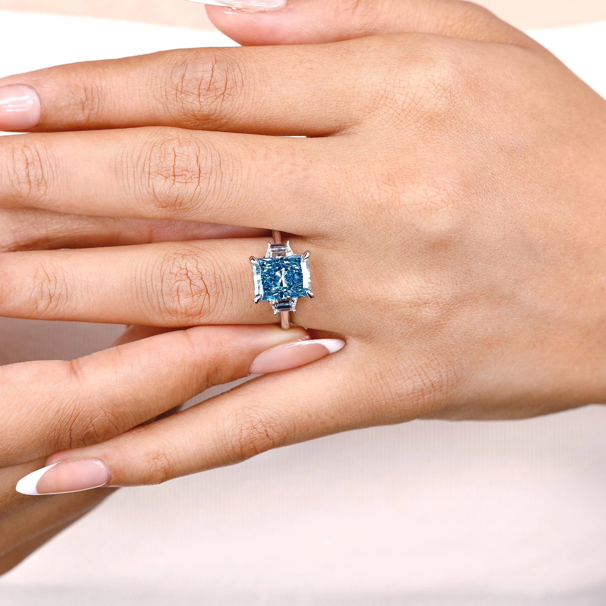 Blue radiant diamond center stone with white gold cathedral band