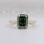 Emerald cut green sapphire bezel set engagement ring yellow gold