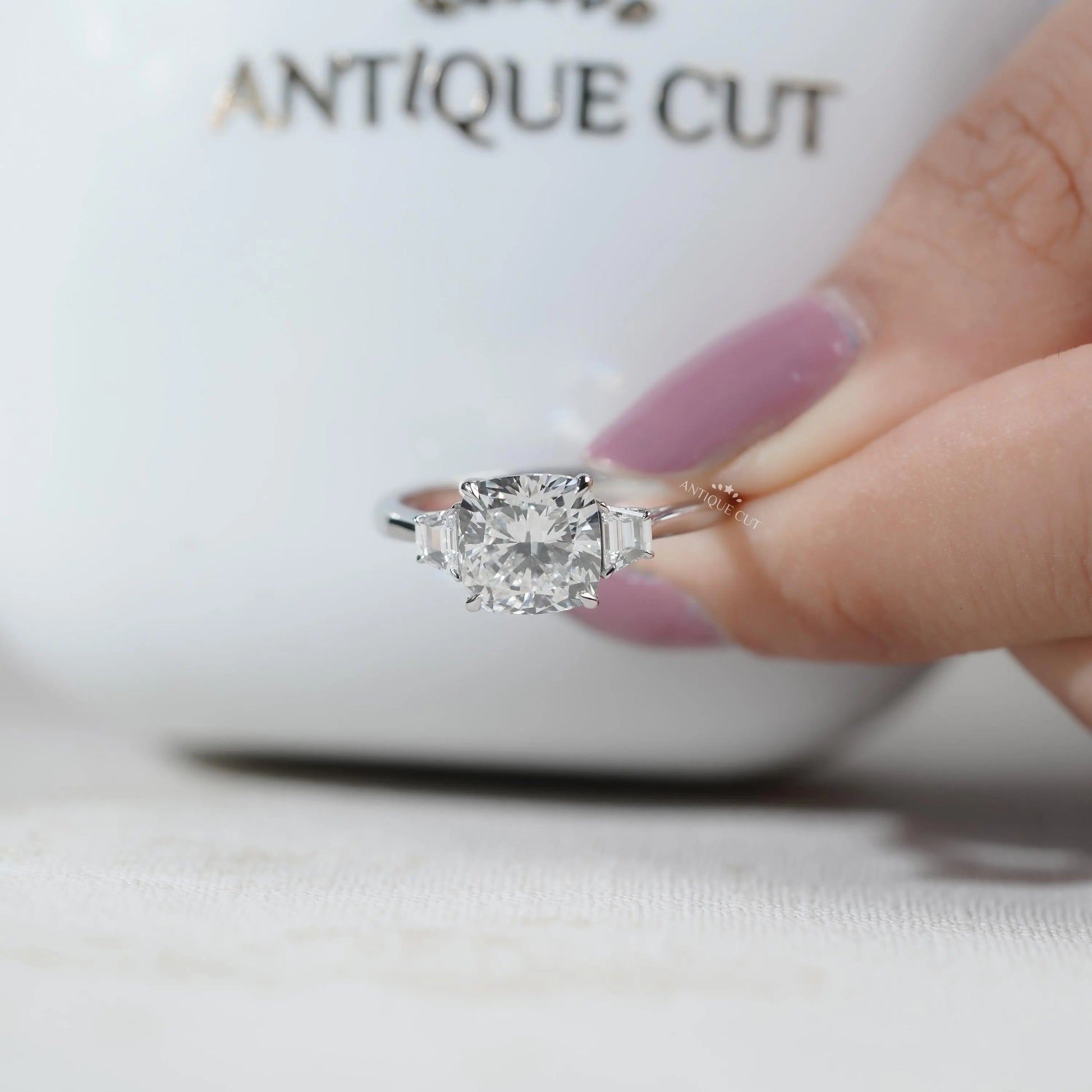 Bridal engagement ring featuring cushion cut center diamond with tapered baguette sides.