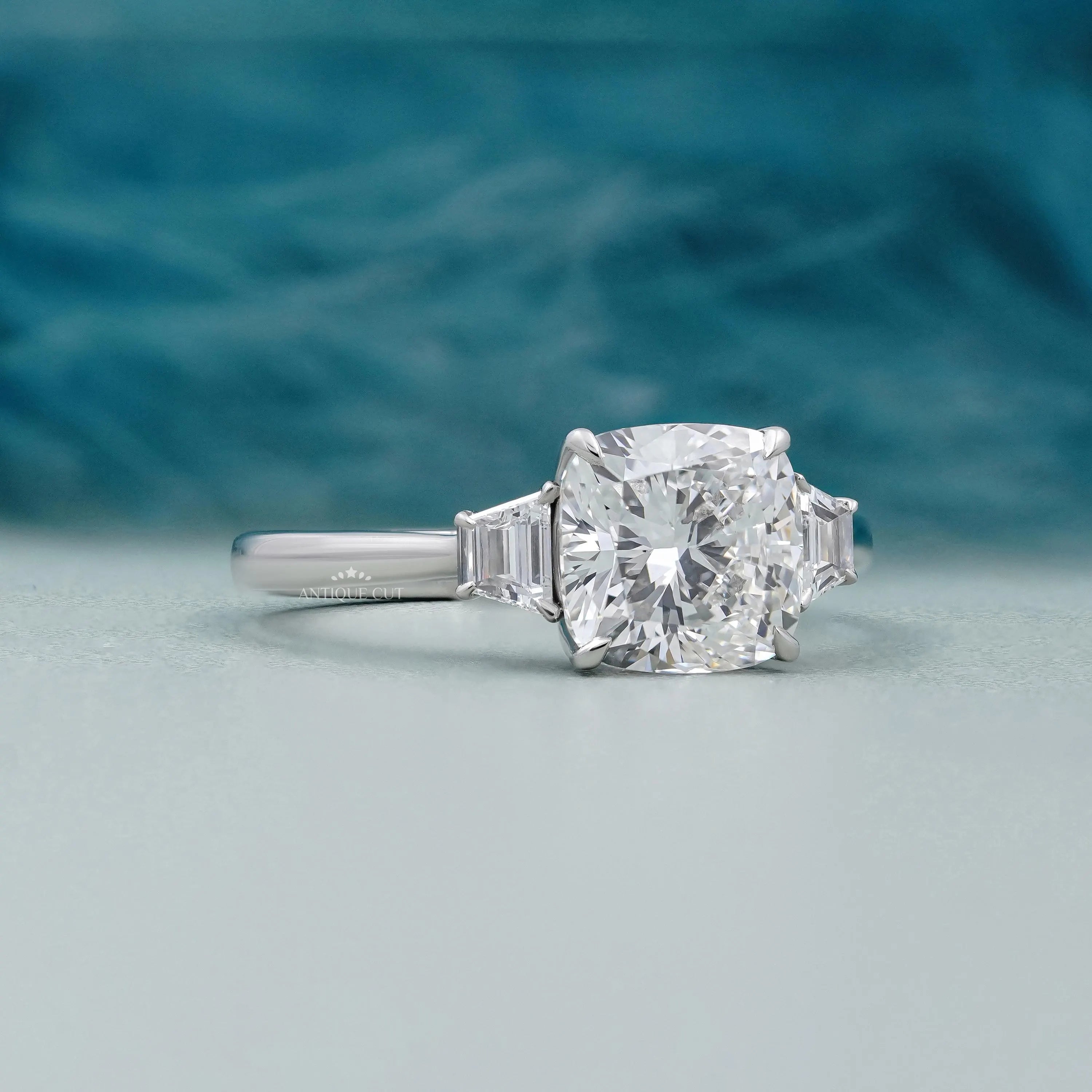 Elegant three-stone engagement ring featuring a cushion cut center and baguette side stones.
