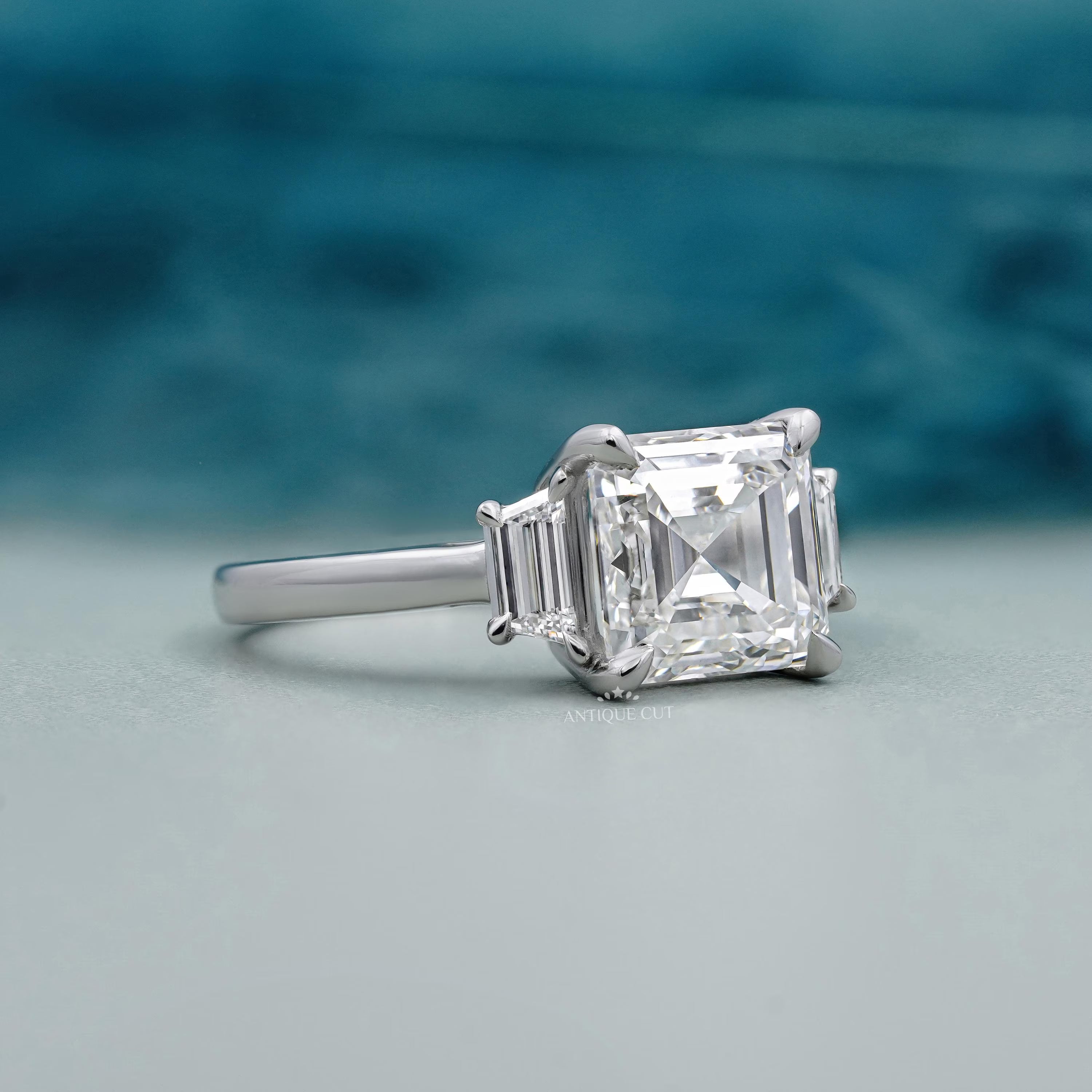 Square emerald cut three stone diamond engagement ring