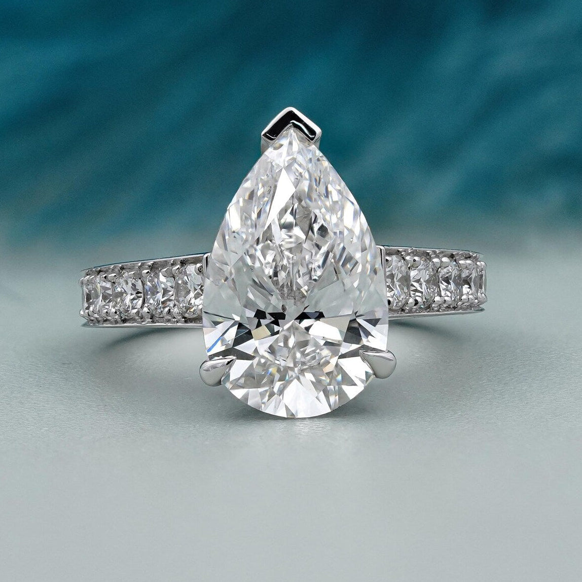 Pear cut engagement ring with pave band in white gold

