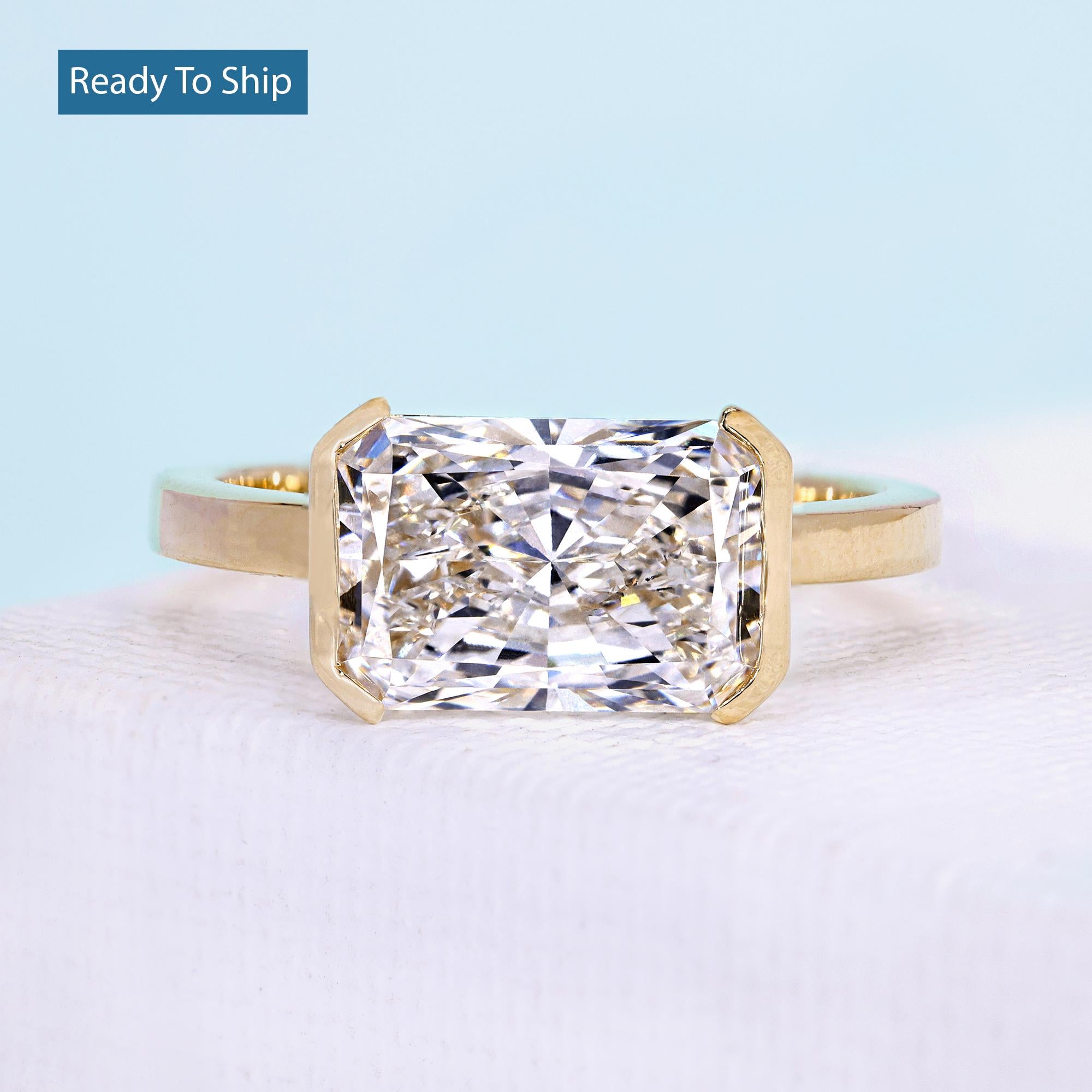 East west radiant cut ring with half bezel engagement setting in yellow gold
