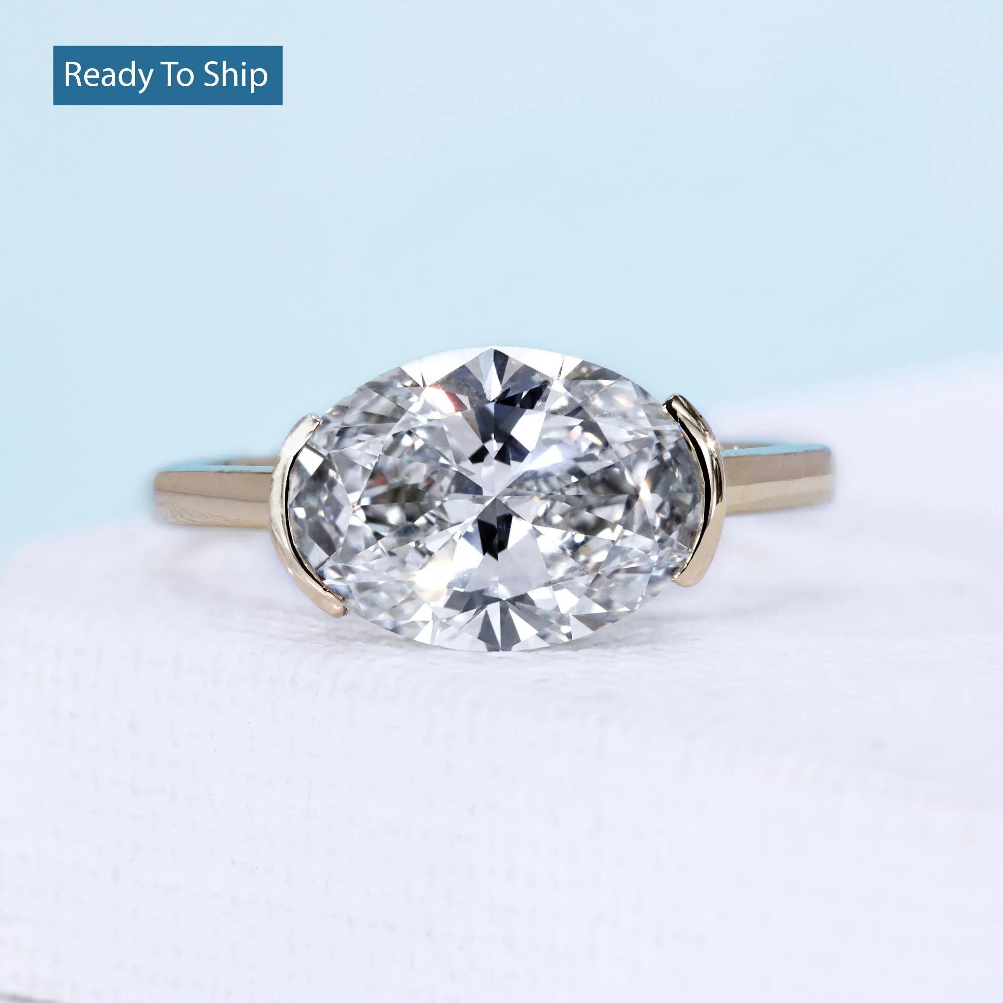 East west oval ring with half bezel setting and yellow gold design
