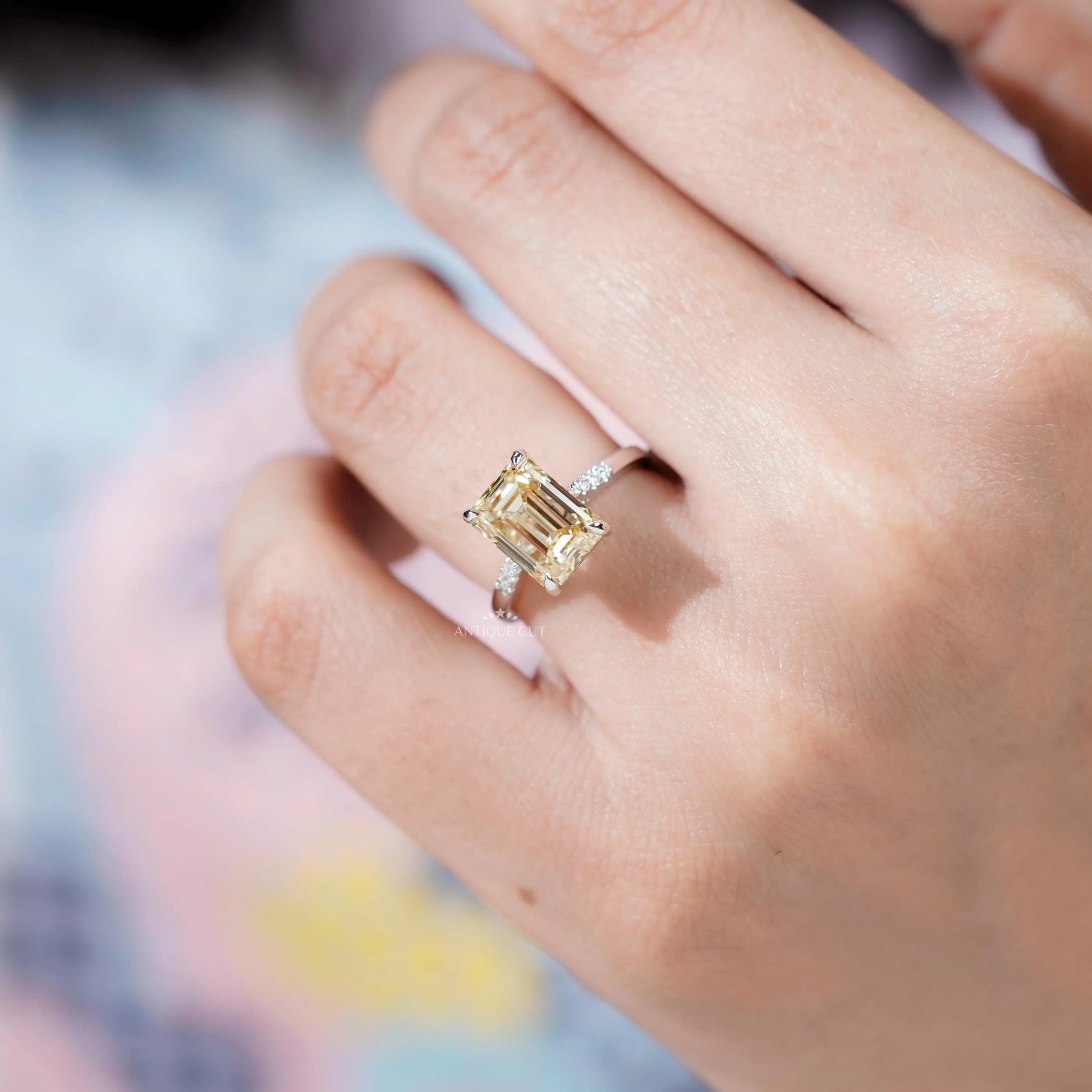 Yellow Emerald Cut Diamond ring featuring round side diamonds.
