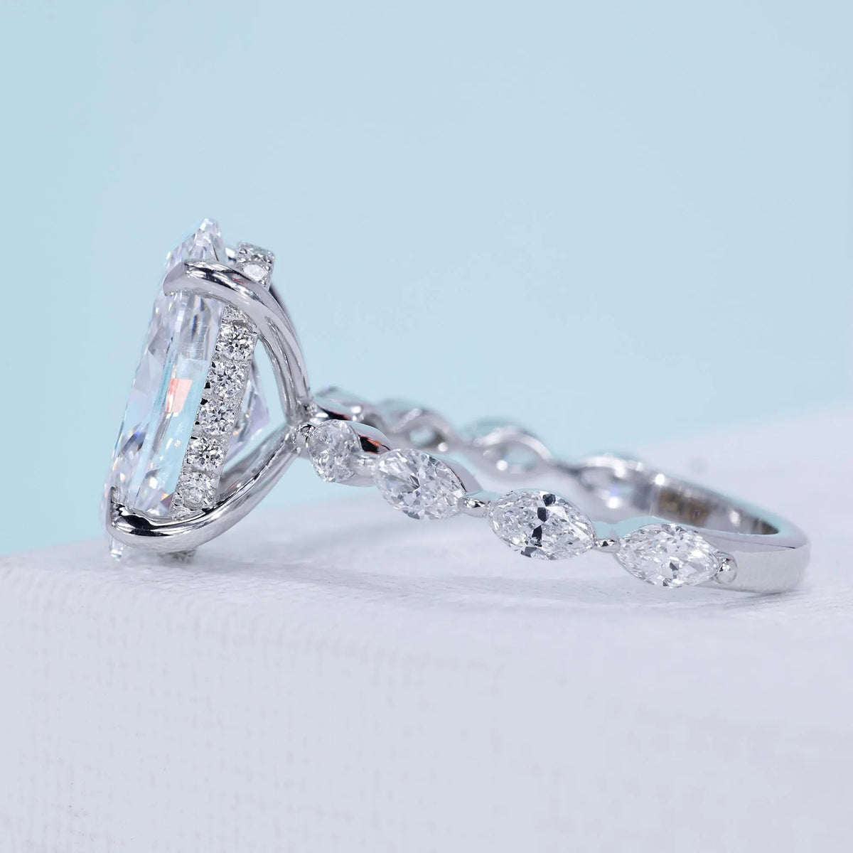 Oval diamond ring with 4 claw prong setting and marquise pavé band
