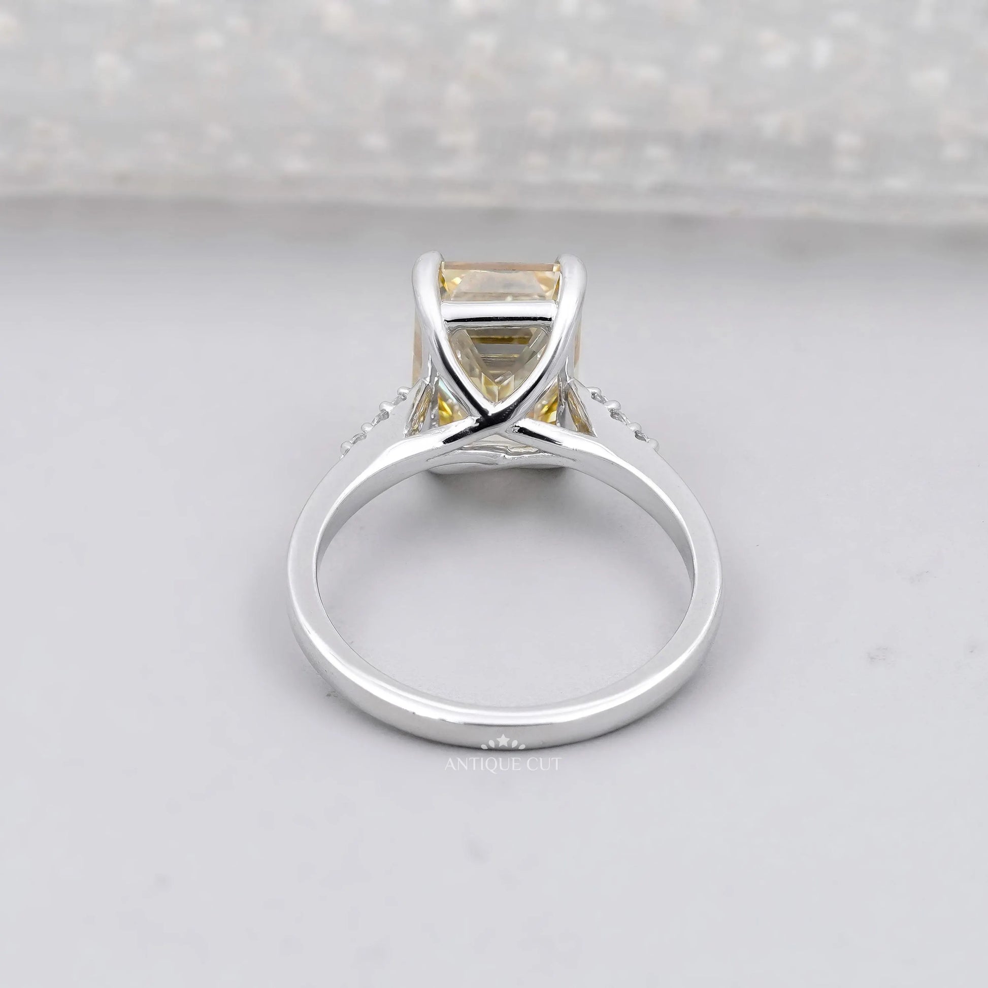 White gold Yellow Emerald Cut Diamond ring with round side stones.