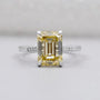 White gold ring with Yellow Emerald Cut Diamond and round side accents.