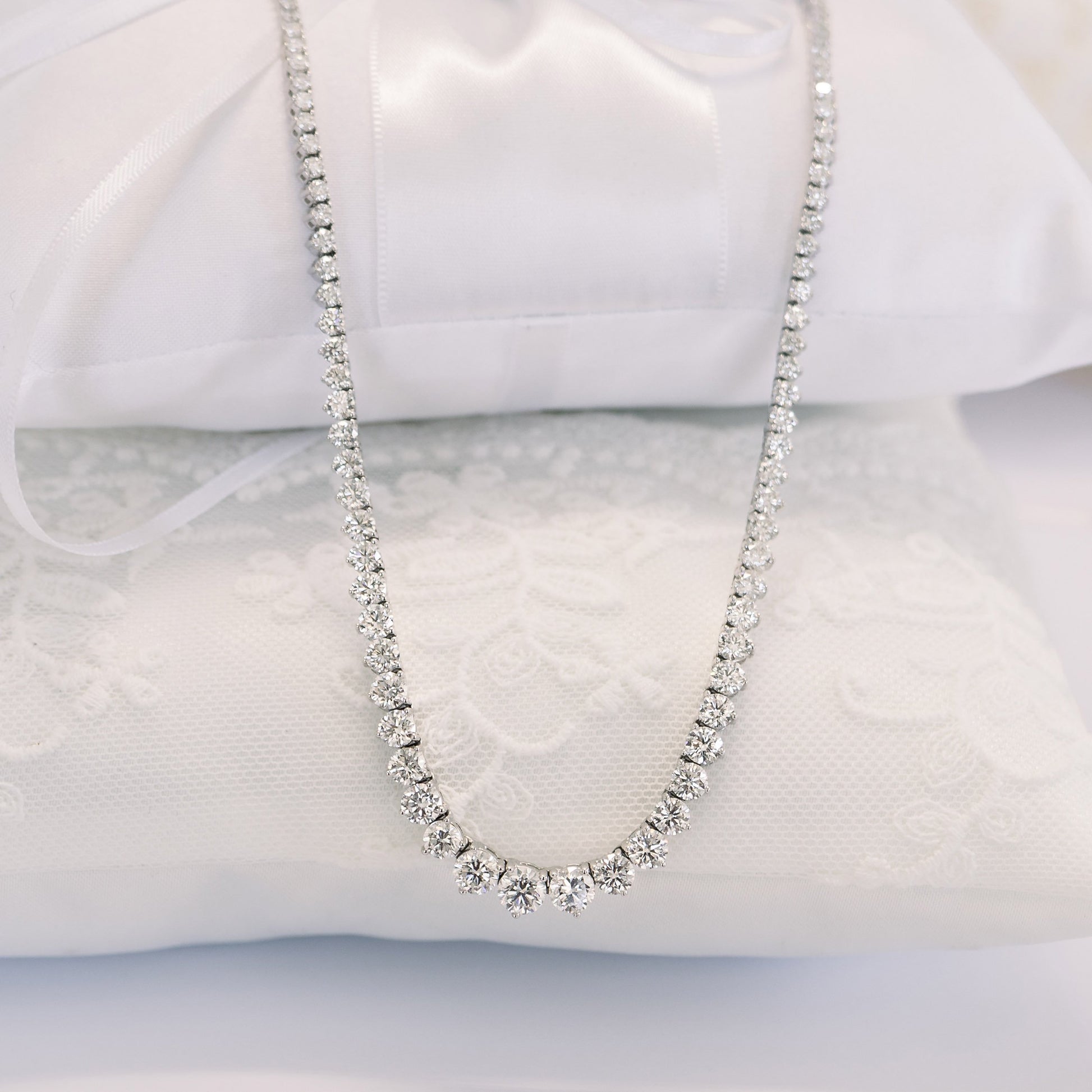 Diamond necklace on white cushions.