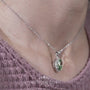 Classic halo pendant featuring green diamond center stone