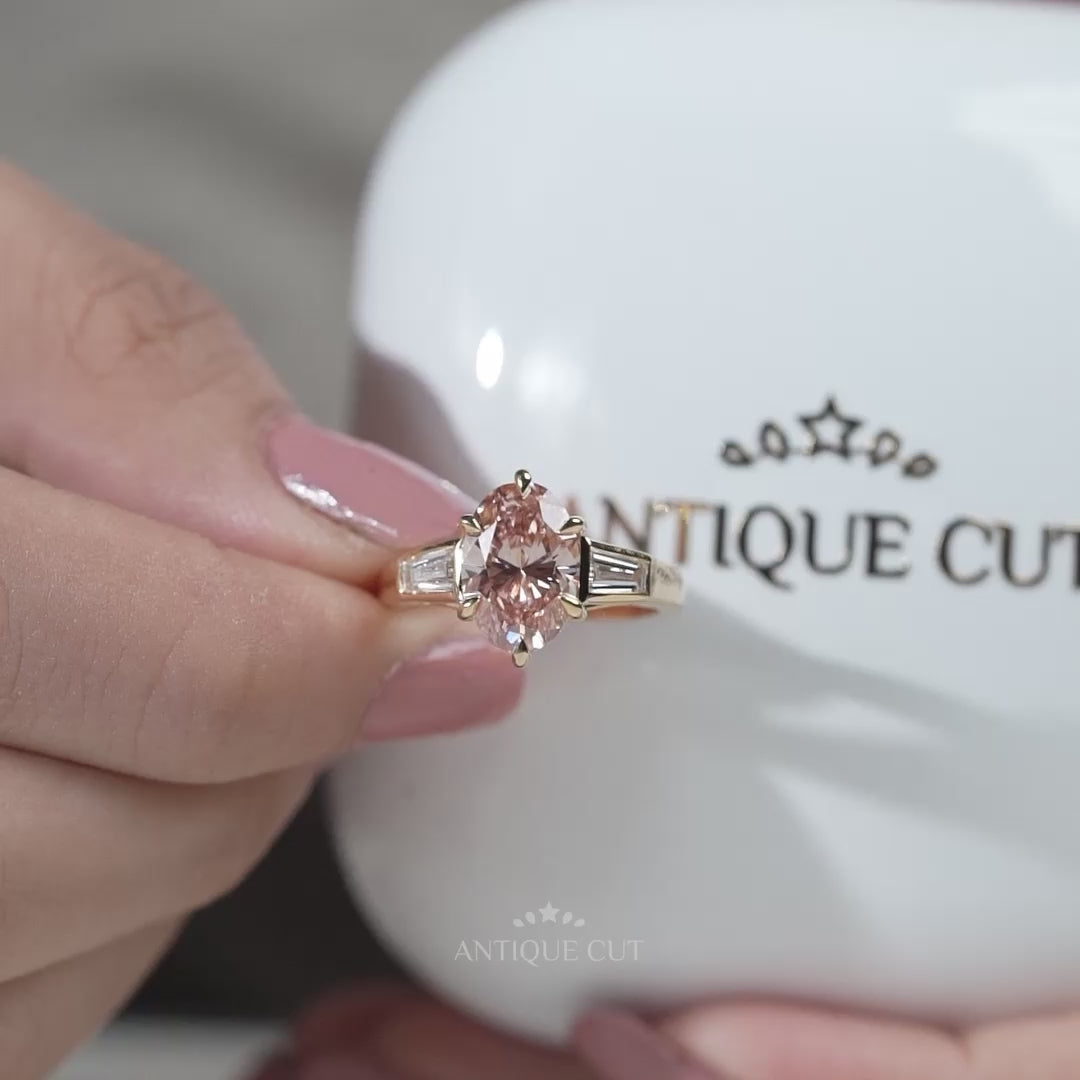 Gold ring with a pink diamond and baguette cut diamonds on a light background