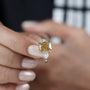 Fancy yellow cushion diamond ring featuring white trapezoid accent diamonds and four-prong design