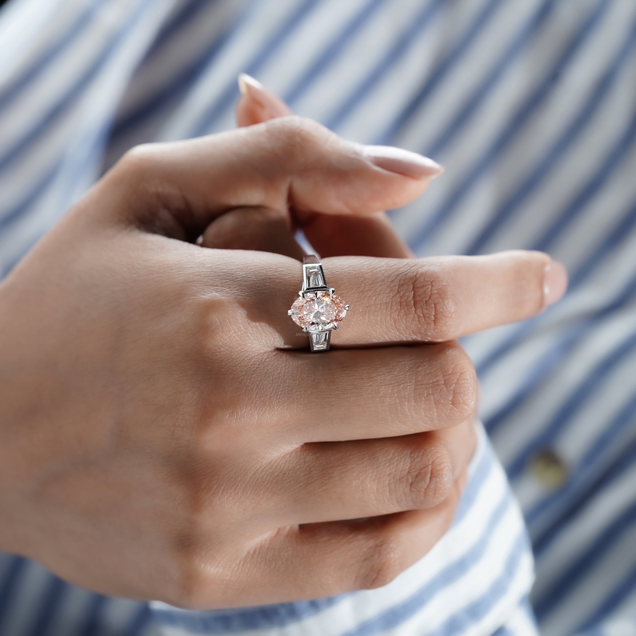 Oval pink diamond three stone engagement ring with baguette side stones