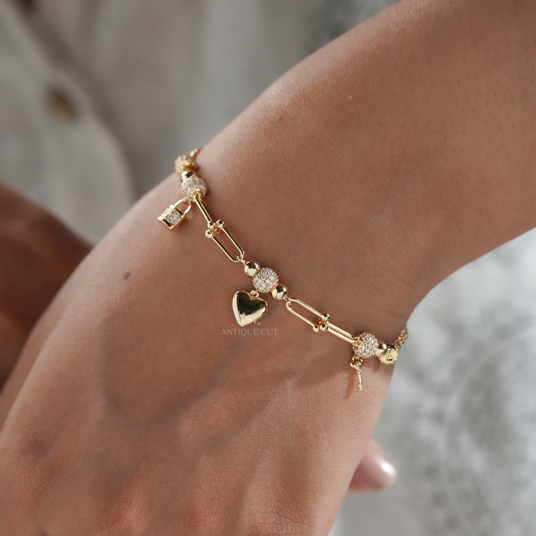 Gold designer charm bracelet featuring diamond heart, lock and key charm details