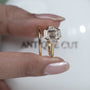 Gold ring with a large central diamond and smaller diamonds on a light gray background

